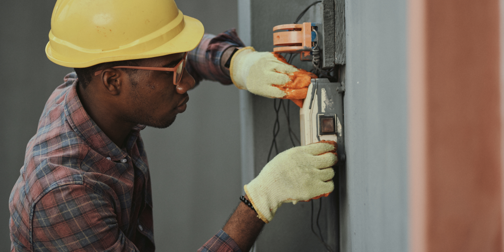 Homme travaillant sur une machine accrochée à un mur.