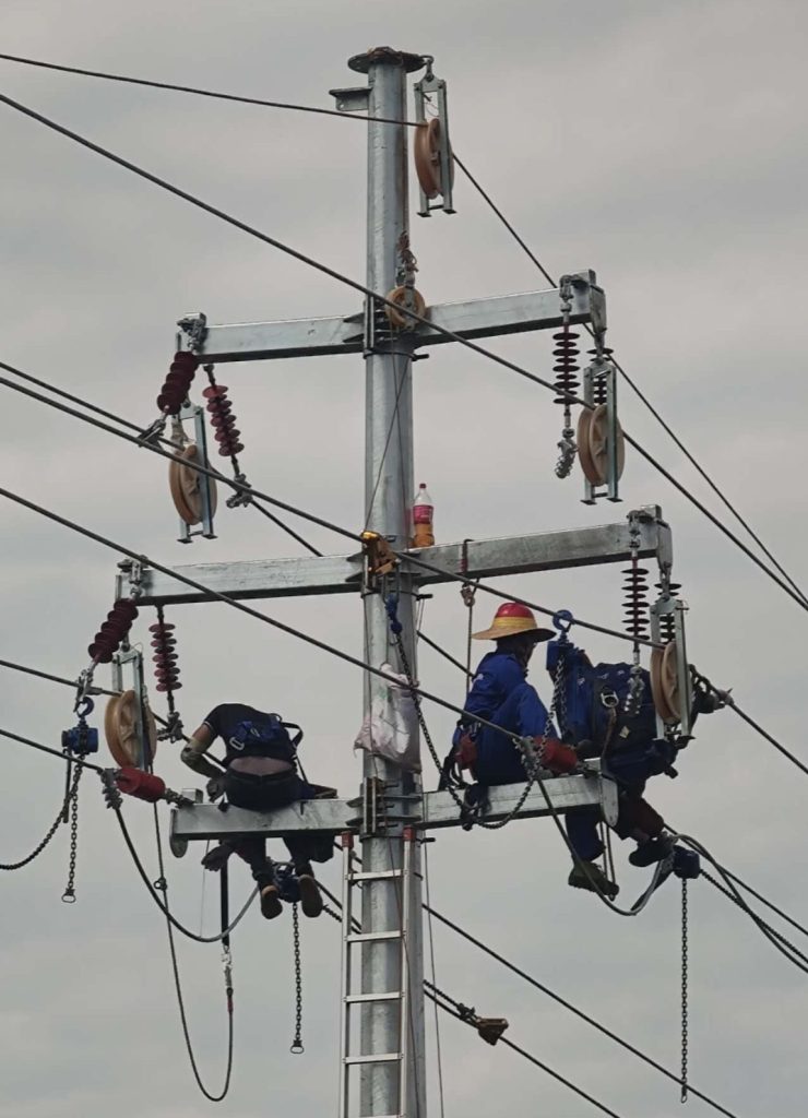 Employé de Sam Power en train d'installer des poteaux électriques