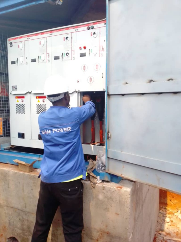 Un employé de Sam Power en train d'installer une cabine électrique.